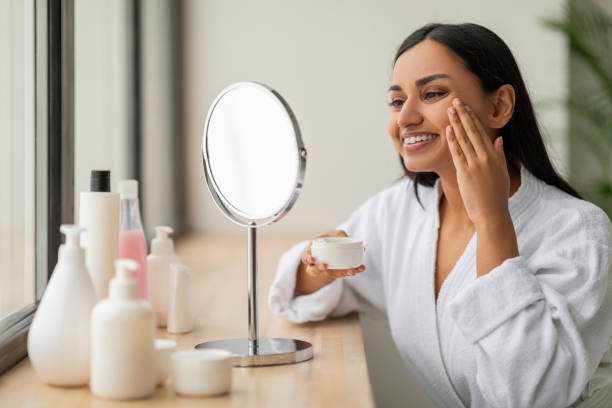 istock Attractive young indian woman in white bathrobe using face cream 2152967379