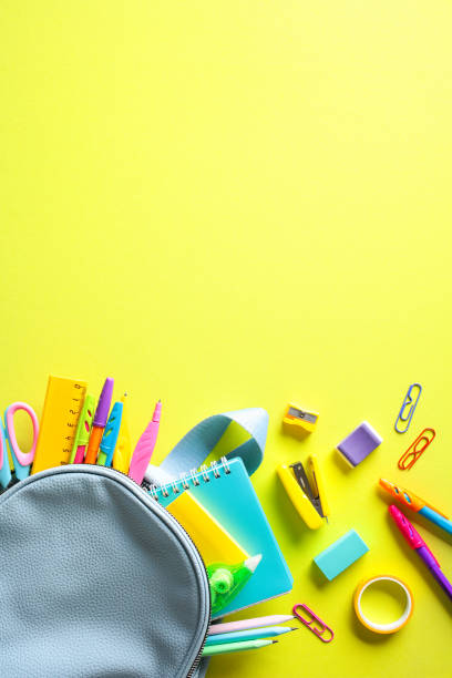 istock Colorful school essentials displayed on a bright yellow backdrop, featuring a blue bag with items like notebooks, pens, and scissors spilling out. Ideal for back-to-school and educational contexts 2152969076