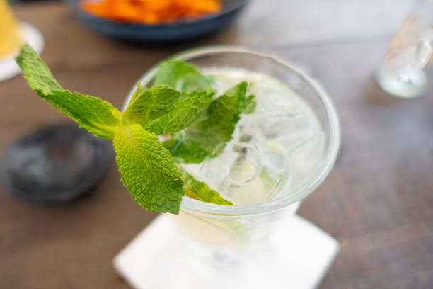 Lemonade with fresh lemon and mint on wooden table background. tall transparent glass