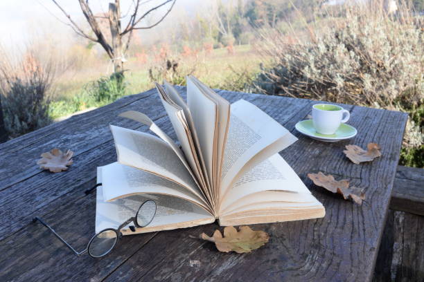 An old open book and a cup of coffee on an old table