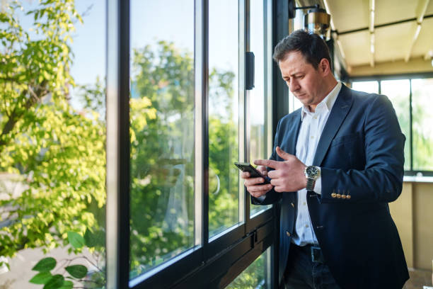 istock Part of a series: Businessman using mobile phone in front of a window. 2152972032