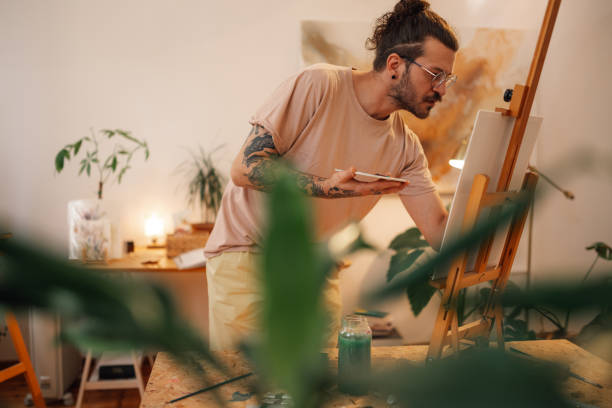 istock Focused hipster artist painting on easel at creative art studio. 2152977293