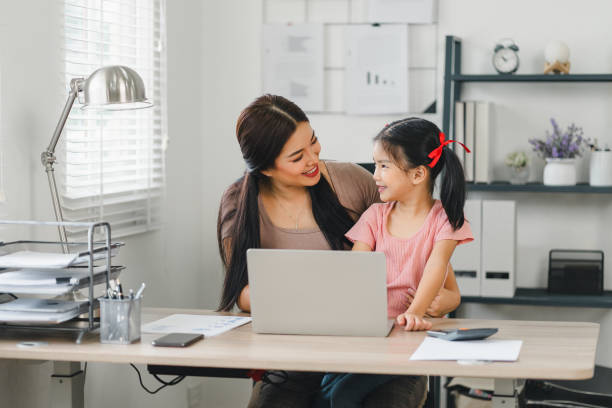 istock Smiling mother and daughter bonding while working with laptop in home office. 2152981708