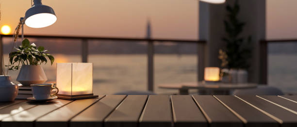 istock A wooden tabletop features decor with a blurred background of a river at sunset. 2152993091