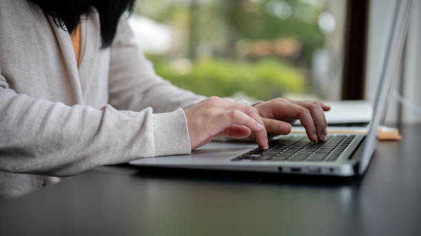 istock A woman typing on her laptop keyboard, working on her laptop computer at a table indoors. 2152994746