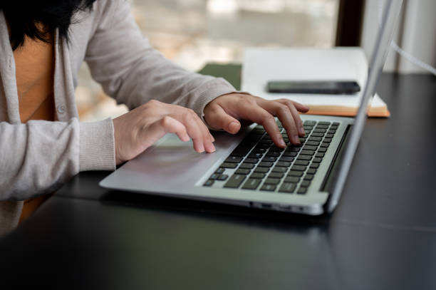 istock A woman typing on her laptop keyboard, working on her laptop computer at a table indoors. 2152994753