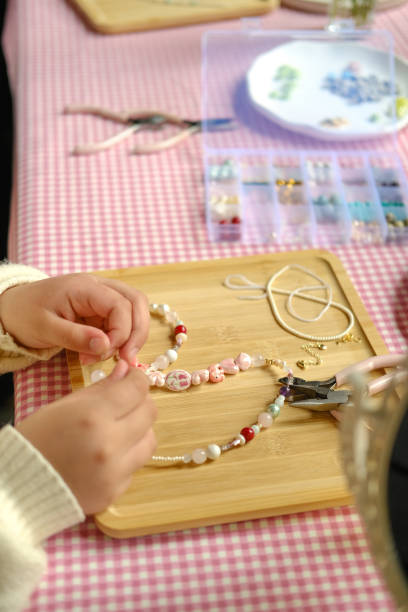 istock Set of multi-colored ceramic and plastic beads for needlework, child and mother are making jewelry at home. Easy and creative craft for children and teenagers. Making bracelets or necklace DIY. 2152995207
