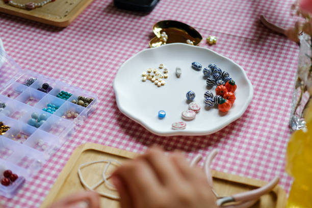 istock Set of multi-colored ceramic and plastic beads for needlework, child and mother are making jewelry at home. Easy and creative craft for children and teenagers. Making bracelets or necklace DIY. 2152995294