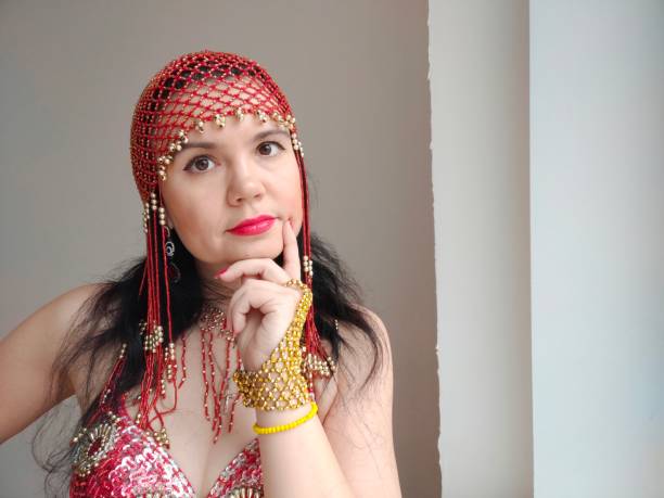 istock A dancer in a red suit is dancing an oriental dance on a white background. Free space for text. Banner. A professional dancer dances oriental belly dance. Sexy woman in red dress dances a seductive dance in a white studio. Isolation. Professional dance 2152997440