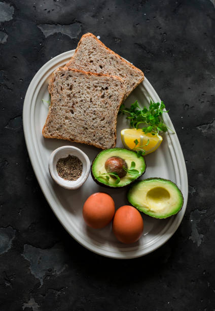 istock Ingredients for making whole-grain toast with avocado, scrambled eggs and microgreens on a dark background, top view 2153005624