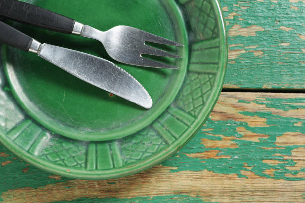 Green plate and cutlery on old wooden background close-up, top view