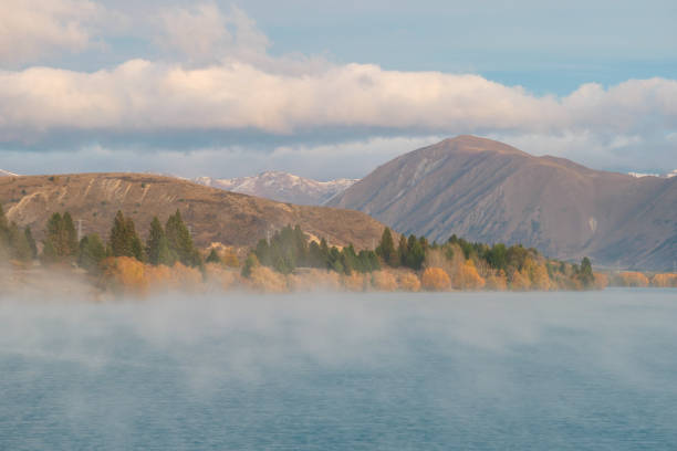 Early morning fog drifts over a lake near Twizel in the Southern Alps of the South Island. Electricity pylons and transmission lines dot the landscape.  This image was achieved with a 1 second exposure and taken on a cold and sunny morning before sunrise on 30 April 2024.