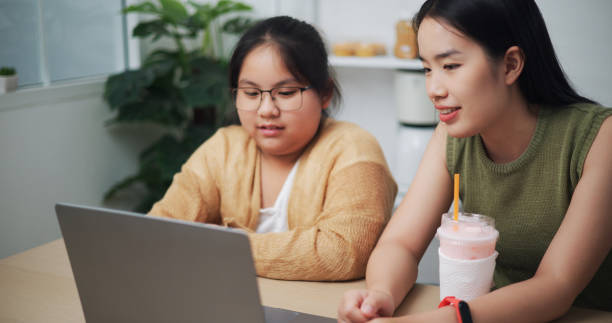 istock Two sisters use laptop computers at home Ideas for everyday use of technology for children. 2153011796