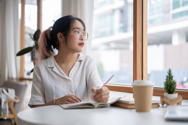 istock A college student is pondering thinking something while doing her homework in a coffee shop. 2153011806