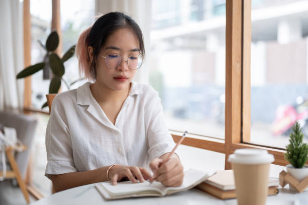 istock A young Asian female college student is doing homework in a coffee shop. 2153011817