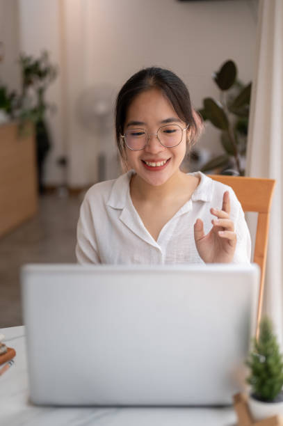 istock A young Asian woman is talking, having an online meeting while working remotely at a coffee shop. 2153011877
