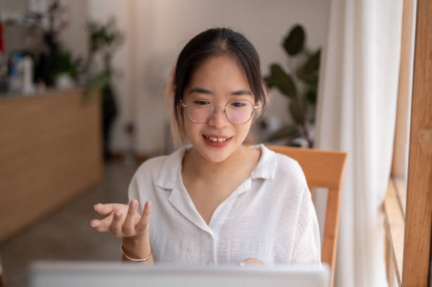 istock A young Asian woman is talking, having an online meeting while working remotely at a coffee shop. 2153011886
