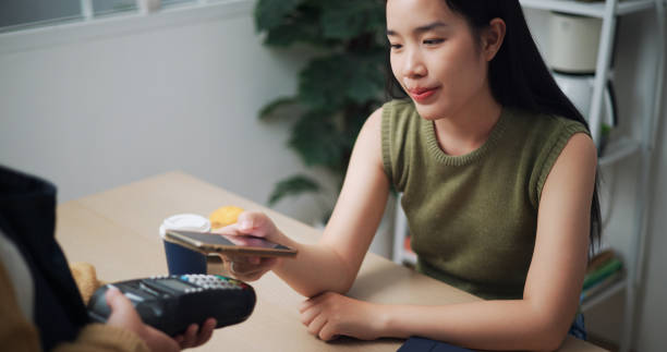istock Young woman pays using a phone app in a restaurant. 2153012117