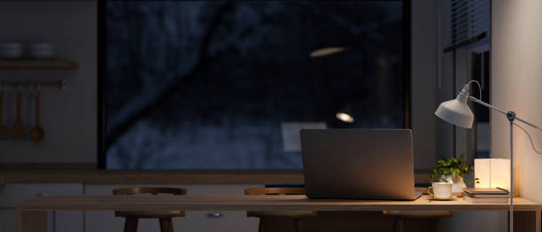 istock A laptop on a dining table in a contemporary kitchen at night with a dim light from a floor lamp. 2153012427