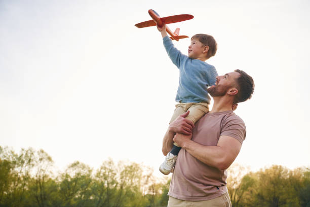 istock Father is holding son that playing with toy plane 2153015552