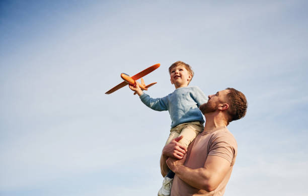 istock Blue sky with white cloud. Father is holding son that playing with toy plane 2153015578