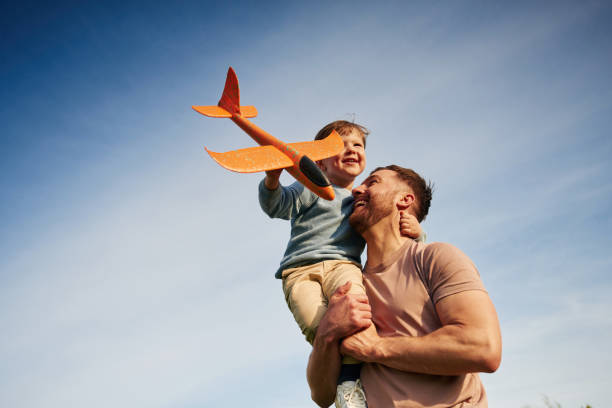 istock Blue sky with white cloud. Father is holding son that playing with toy plane 2153015625