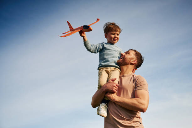 istock Blue sky with white cloud. Father is holding son that playing with toy plane 2153015626