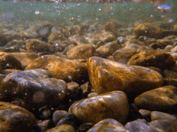 istock Pebbles stone underwater below water surface near lake shore, natural scene 2153015888