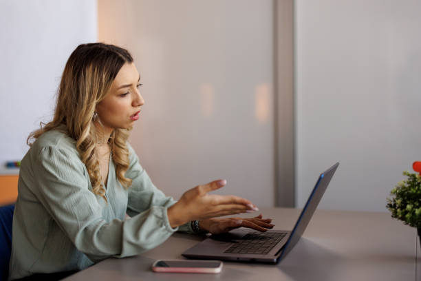 istock Young woman teleconferencing on laptop while working from modern office 2153016927