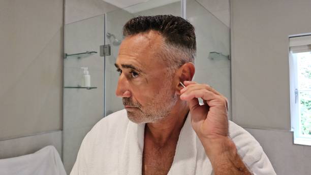 Man in White Robe Putting Ear in Mirror