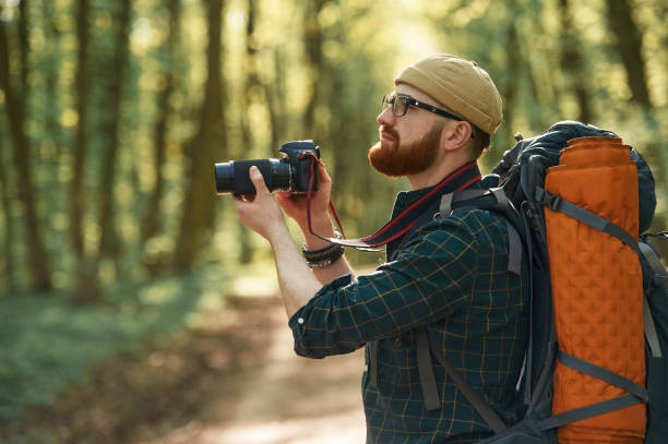 istock Photographer with camera. Bearded man is in the forest at daytime 2153021149