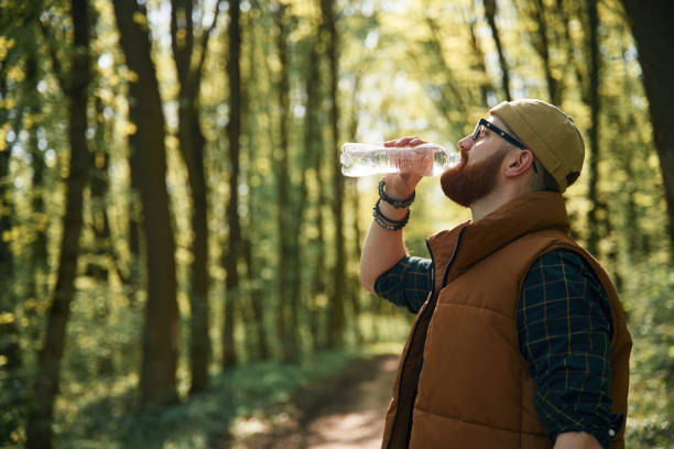 istock Drinking a water. Bearded man is in the forest at daytime 2153021314
