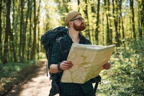 istock Reading the map, looking for a way. Bearded man is in the forest at daytime 2153021800