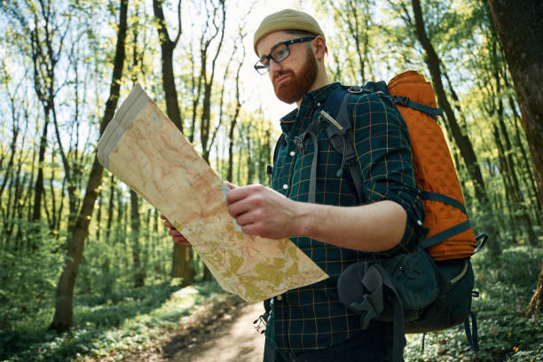 istock Reading the map, looking for a way. Bearded man is in the forest at daytime 2153021889