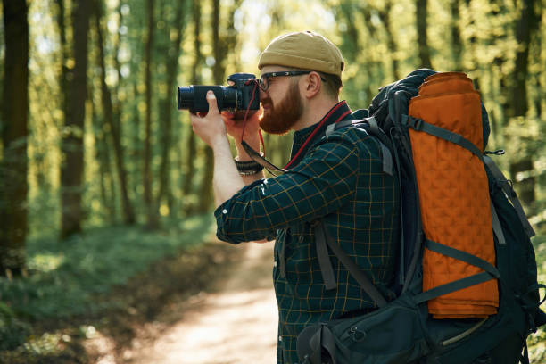 istock Photographer with camera. Bearded man is in the forest at daytime 2153022150