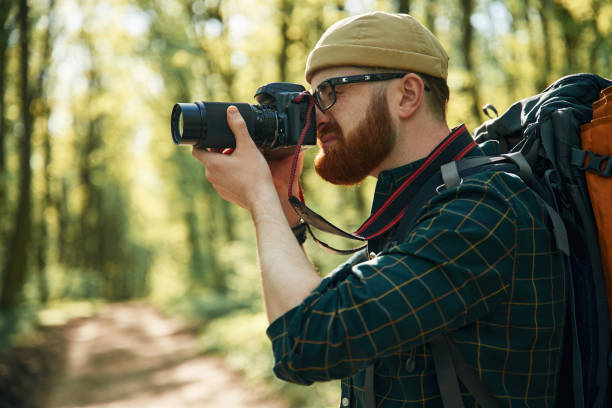 istock Photographer with camera. Bearded man is in the forest at daytime 2153022192