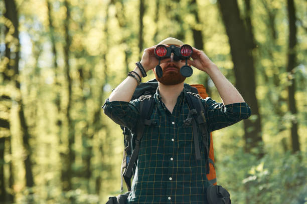 istock Discovering new place with binoculars. Bearded man is in the forest at daytime 2153023214