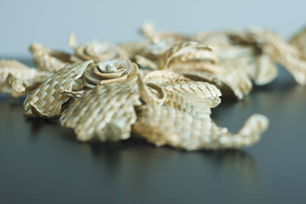 Branch with leaves and flowers is made of straw. Decoration of straw. Straw wall decoration. Straw weaving. Shallow depth of field (DOF)