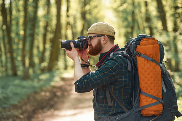 istock Photographer with camera. Bearded man is in the forest at daytime 2153024561