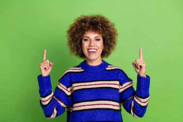 istock Portrait of cute girl with perming coiffure dressed knit pullover indicating at discount empty space isolated on green color background 2153028242