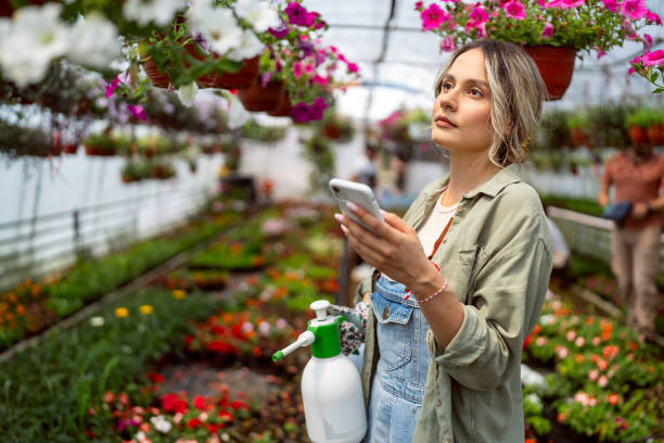 istock Female florist using mobile phone while working at the flower nursery 2153033021