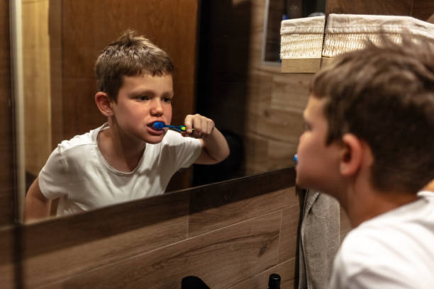 istock Caucasian young boy is standing in front of a mirror, diligently brushing his teeth. He is focused on his reflection, holding a toothbrush and toothpaste. 2153036068