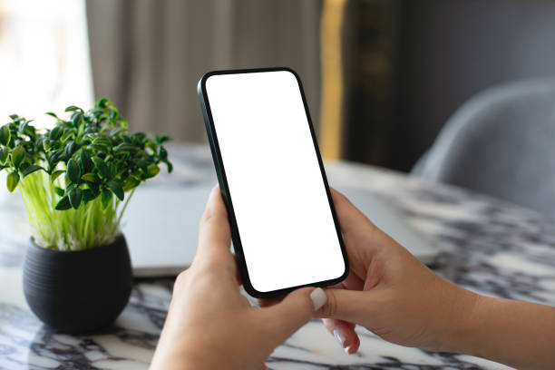 istock Female hand hold phone with isolated screen background table office 2153036194