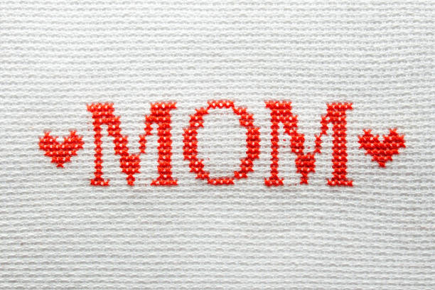 Close-up of female hands cross stitching on a white canvas. A woman embroiders the national symbols of Ukraine with a cross.