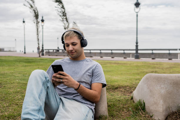 istock Young man with headphones using mobile phone outdoors 2153038526