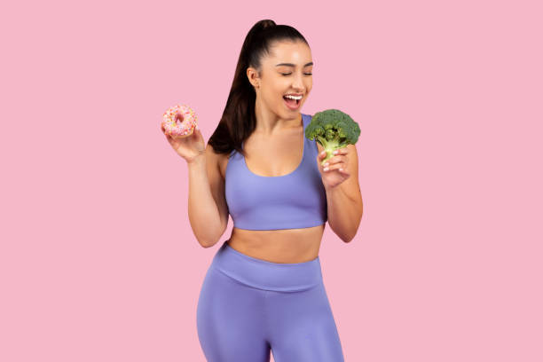 istock Cheerful woman choosing between donut and broccoli 2153042830