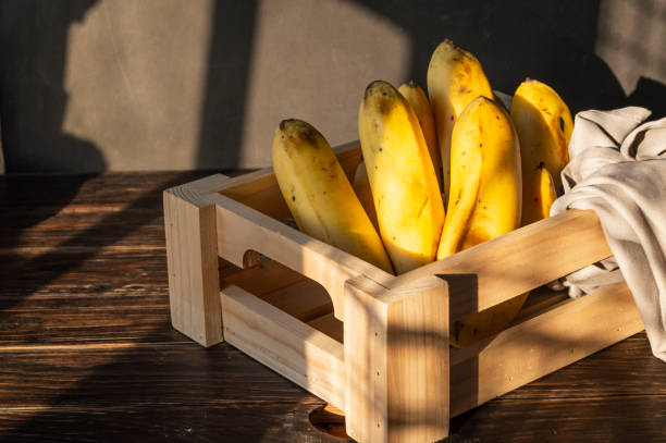 Ripe yellow bananas in a sweet box with vitamins on a wooden background