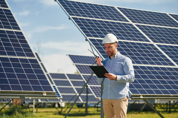 istock Using walkie talkie and holding notepad. Engineer with photovoltaic solar panels outdoors at daytime 2153046200