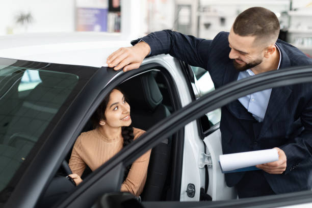 istock Salesman explaining car features to a woman 2153047341