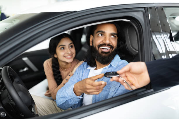 Cheery young family buying new vehicle at modern showroom Smiling indian millennial couple taking car key from auto salesman, sitting inside modern automobile at dealership, closeup. Cheery young family buying new vehicle at modern showroom happy car asian stock pictures, royalty-free photos & images